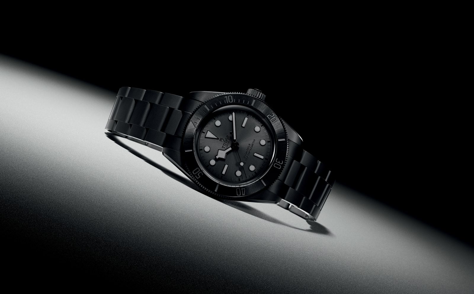 Montre de plongée noire sur bracelet céramique, posée dans un faisceau de lumière